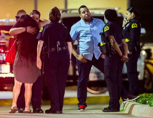 Una mujer recibe el abrazo de un oficial afera de la sala de emergencia del hospital Texas...