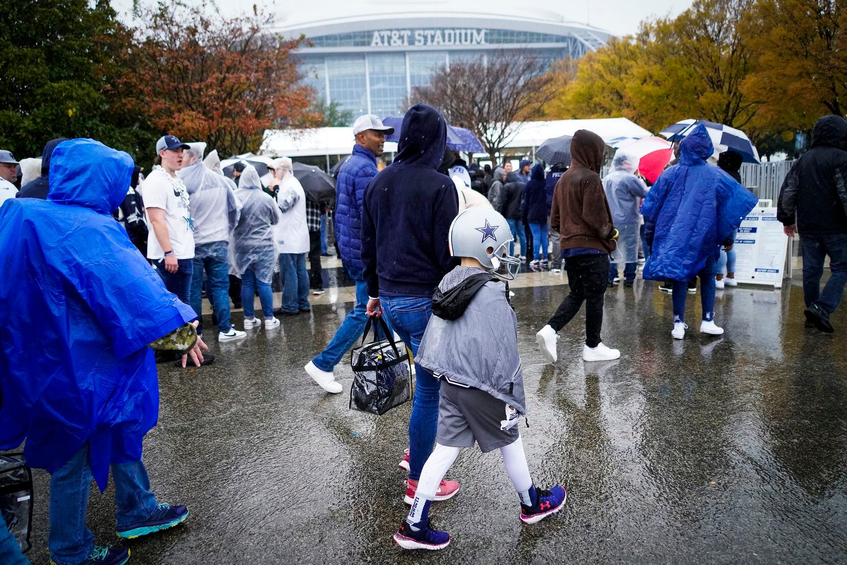 Fans head to the stadium in the rain before an NFL football game between the Dallas Cowboys...