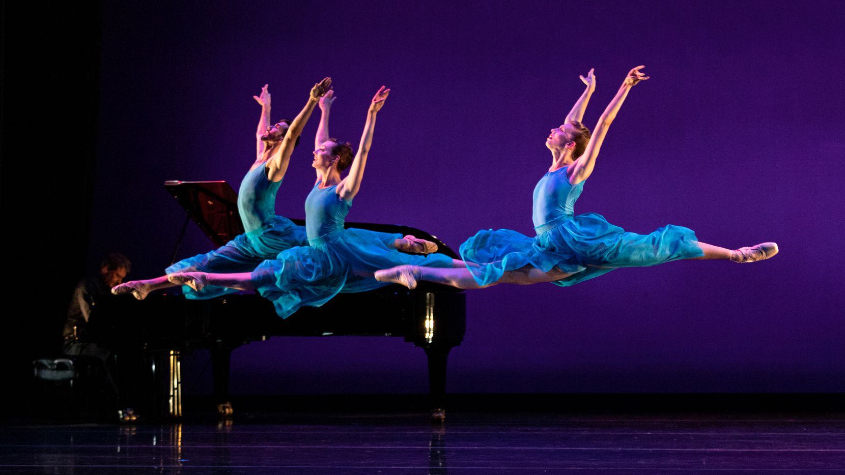 Three female ballet dancers leap across the stage.