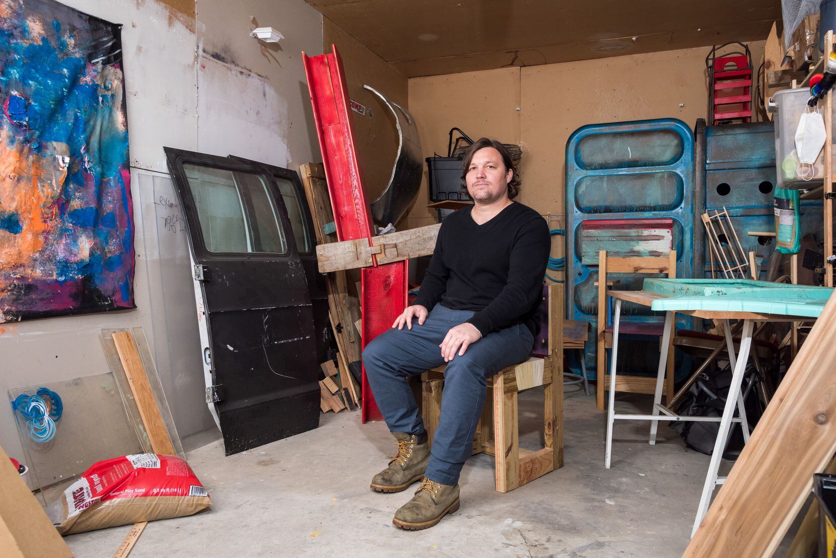 Artist Kasey Short sits in his studio with his art.