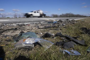 Drivers pass by debris, where six people, including two children, were killed and three...