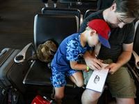 Sam Smith, 6, and his father Josh draw a car together while waiting during a four hour delay...