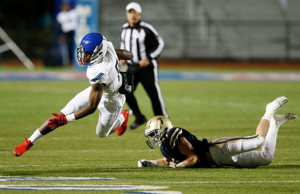 Trinity Christian's Marques Buford (8) is tripped up by Austin Regents William Raeder (7)...