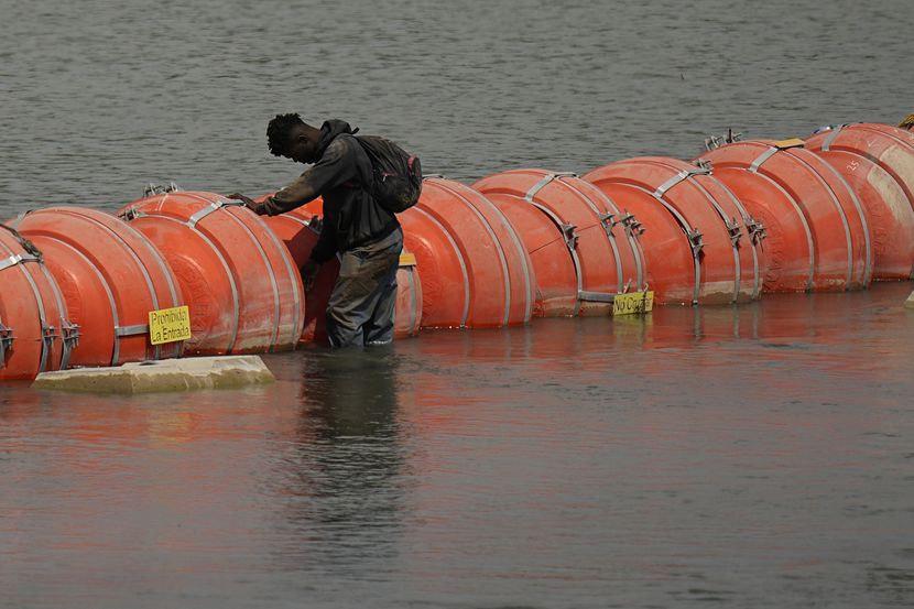 A migrant from Colombia stands at a floating buoy barrier as he looks to cross the Rio...