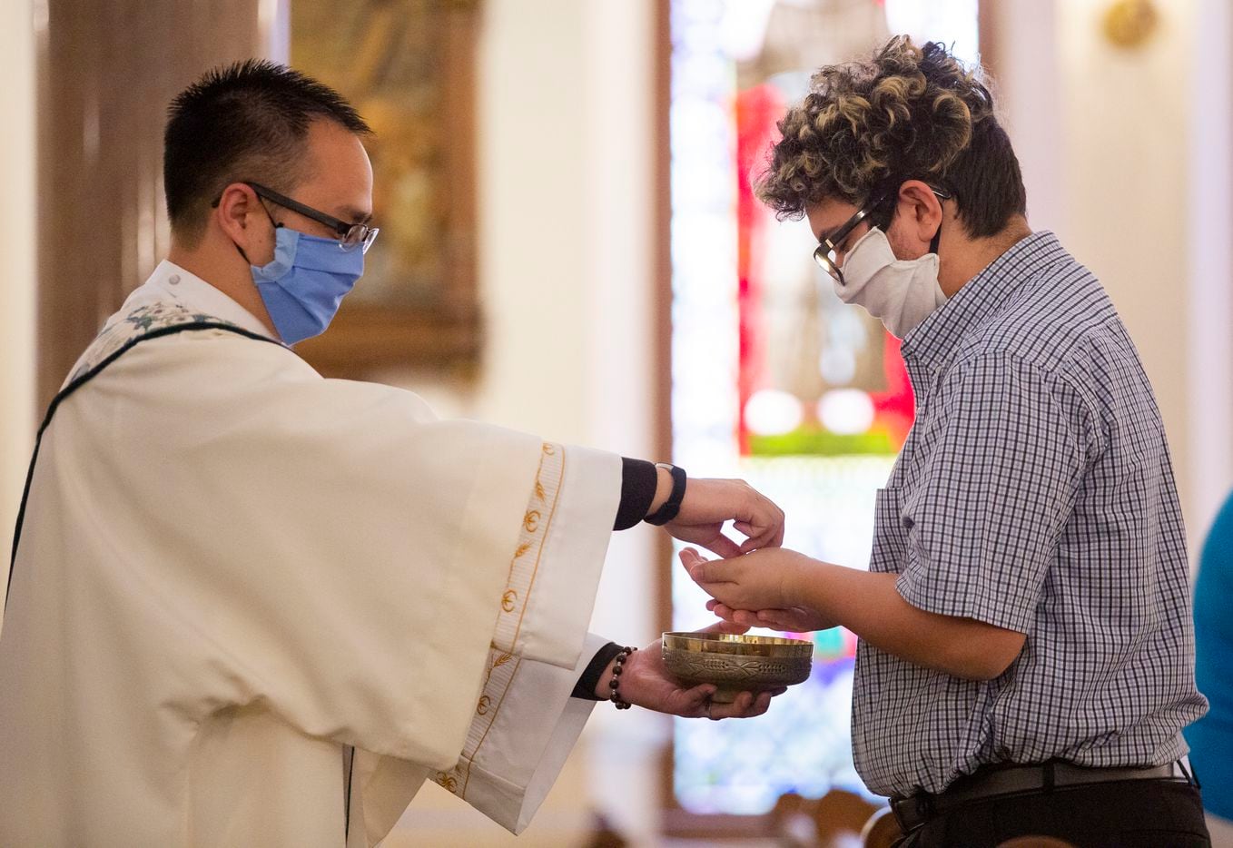 Deacon Linh Nguyen (left) delivers communion during mass at St. Patrick Cathedral.