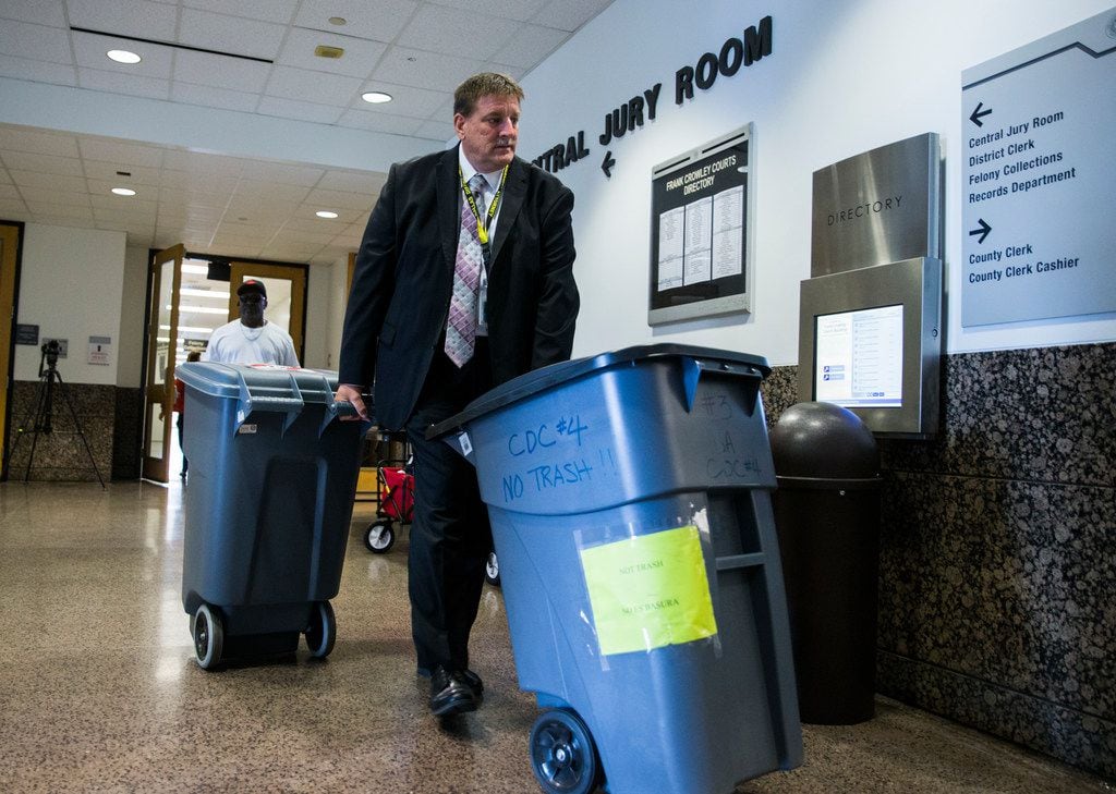 Large bins filled with questionnaires are wheeled out of the Central Jury Room after potential jurors for the Amber Guyger trial filled them out on Friday at the Frank Crowley Courts Building in Dallas.