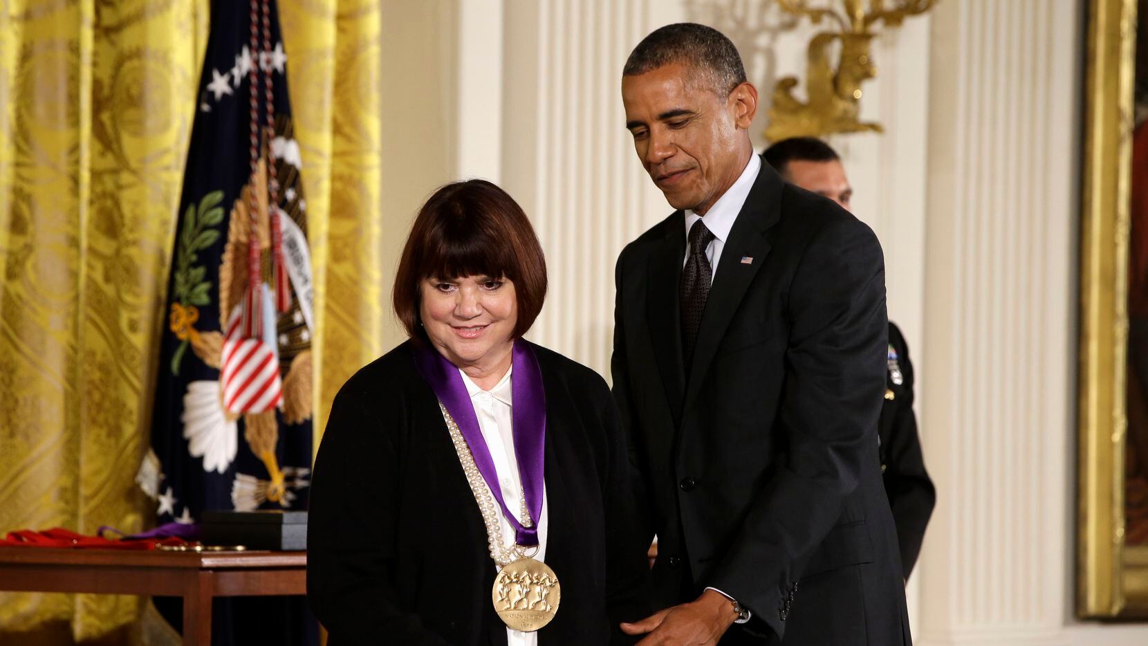 President Barack Obama helps singer Linda Ronstadt off stage in the East Room of the White...