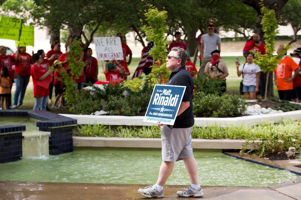Ron Hansen of Coppell carries a sign in support of  State Rep. Matt Rinald as opponents of the SB4 law, Texas' "sanctuary city" legislation, rally outside Rinaldi's offices on Wednesday, May 31, 2017, in Farmers Branch, Texas.