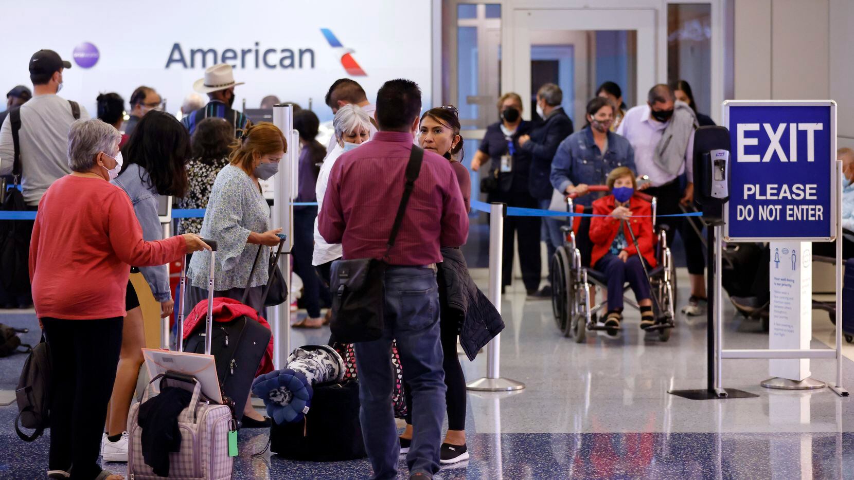 Passengers wait in line to rebook their canceled American Airlines flight in Terminal D at...