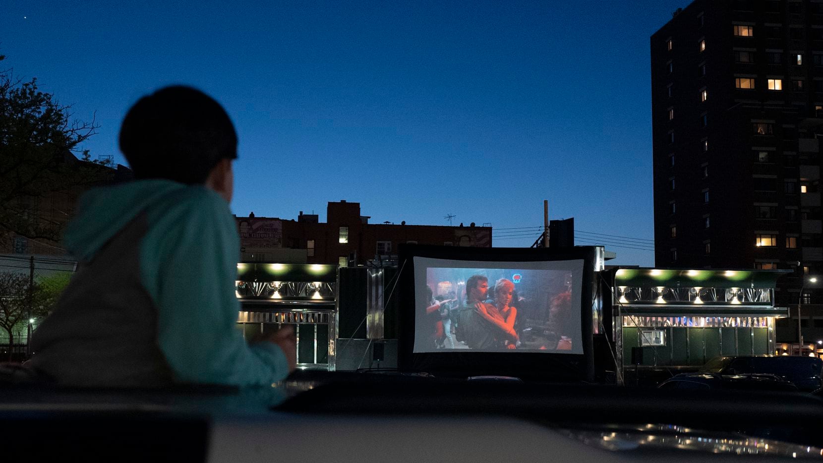 A boy stands up through a car's sunroof to watch "Dirty Dancing," at a drive-in movie held...