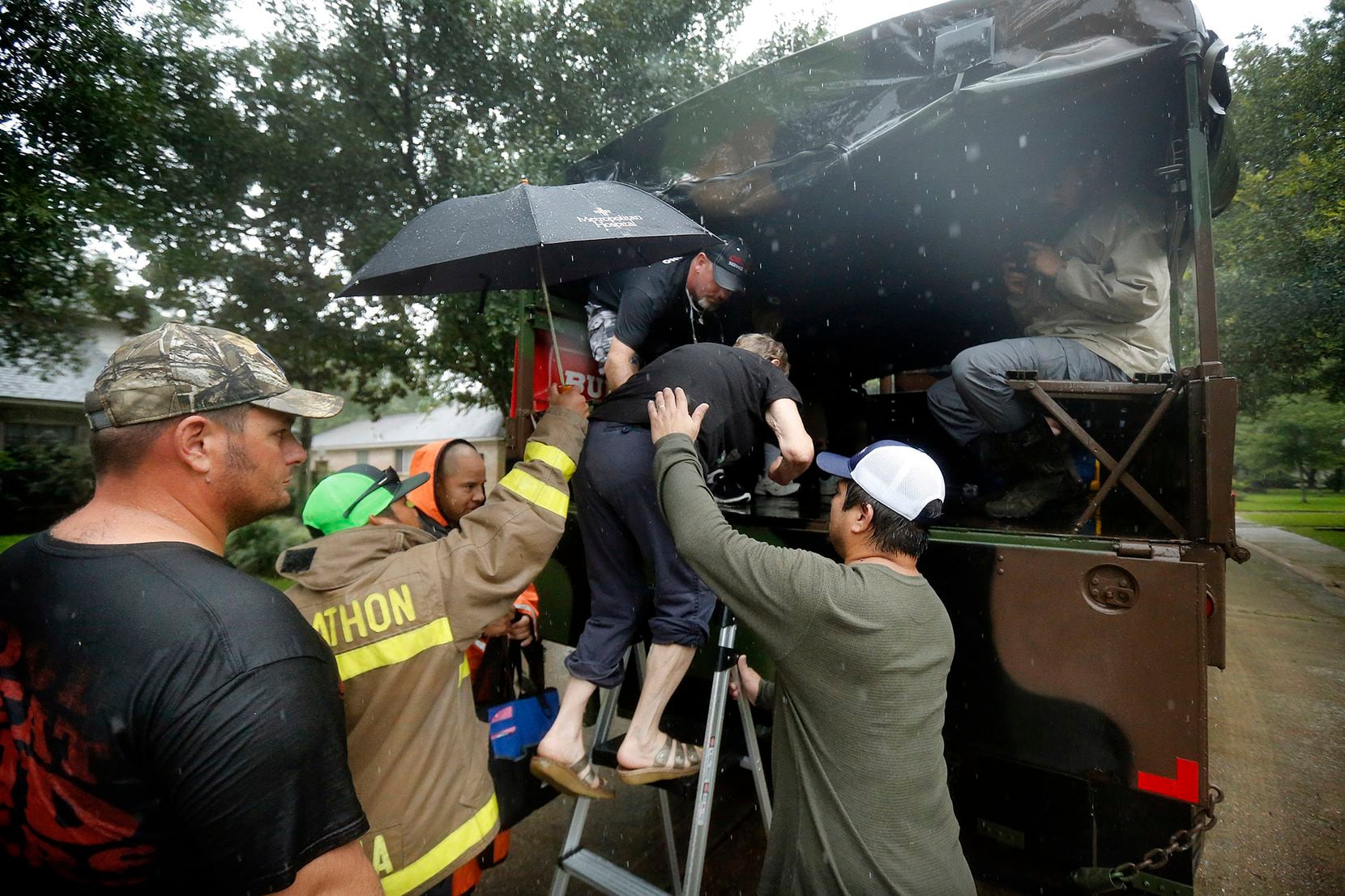Volunteers help Carla Babinski into the back of a military-type transport truck as she took...