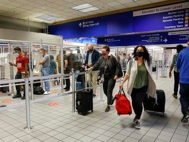 Travelers walk past a TSA checkpoint in Terminal C at DFW International Airport on Oct. 20, 2021.