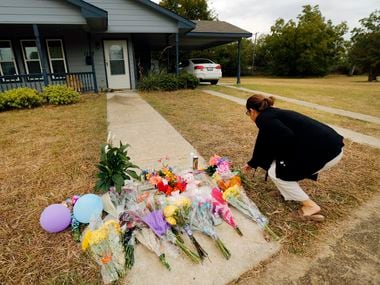 Anastasia Gonzalez of Burleson leaves flowers on the sidewalk in front of Atatiana Jefferson's home in Fort Worth.