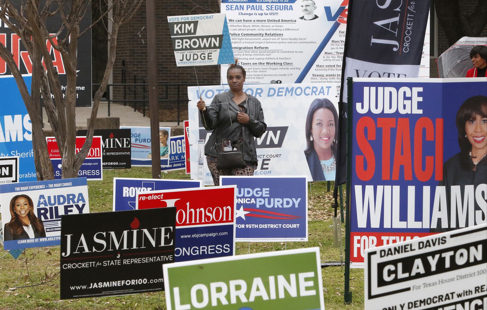 Cheryl Miller holds a “Kim Brown for Judge" sign as she stands with other candidates signs in the parking lot of  Dallas County Government Center on Super Tuesday. Officials are seeking a recount after finding a discrepancy in the vote count. 