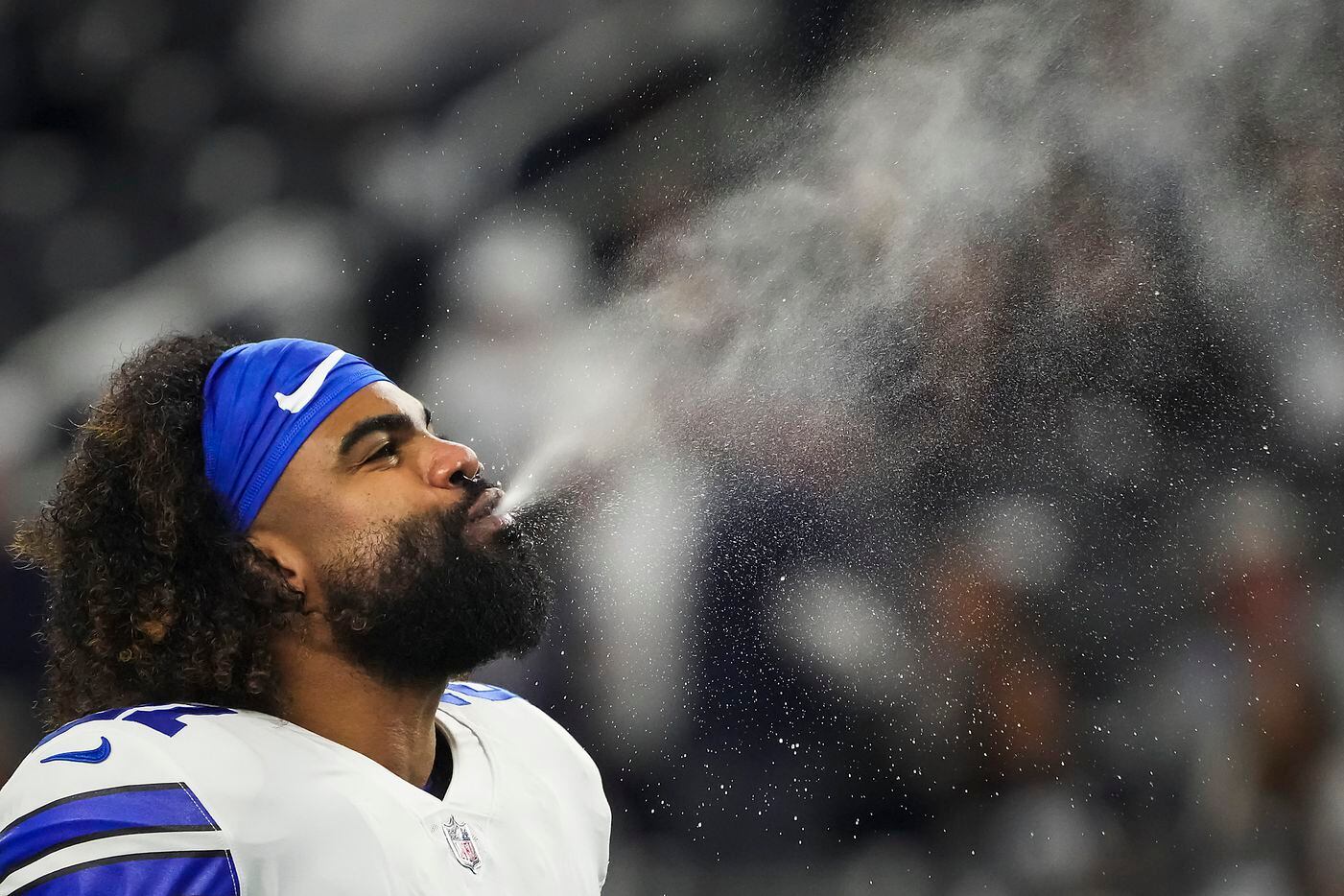 Dallas Cowboys running back Ezekiel Elliott spits water as the team warms up before an NFL...