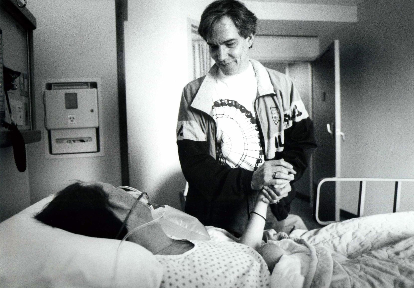 Don Maison Jr., executive director of AIDS Services of Dallas, holds the hand of a Ewing...