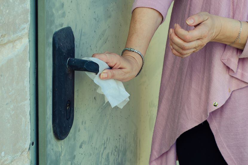 Una mujer abriendo una puerta con un pañuelo.