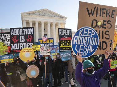 Demonstrators gather at the U.S. Supreme Court as the justices hear arguments in Dobbs v....