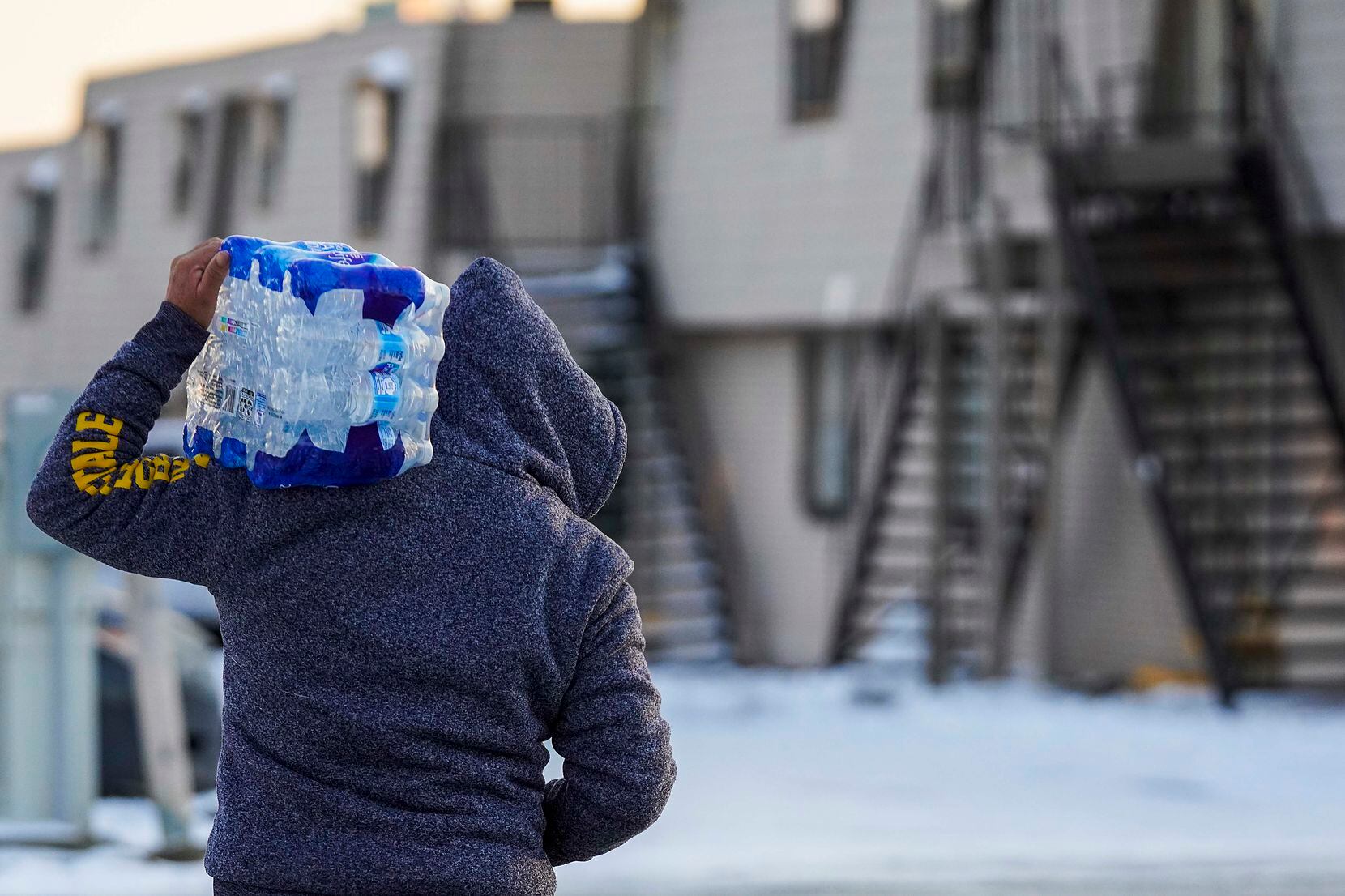 A man walked home with drinking water that was distributed at the nonprofit Literacy Achieves in the Vickery Meadows neighborhood in Northeast Dallas on Feb. 18 as area residents reeled from the effects of the winter storm.