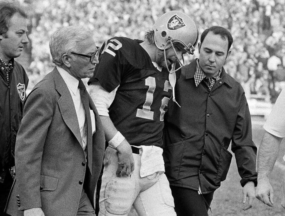 Ken Stabler is helped from the field after a hard tackle in the third quarter of the 1976...
