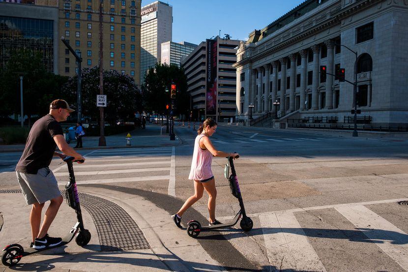 People ride rental scooters along Commerce Street in downtown Dallas on July 13, 2019....