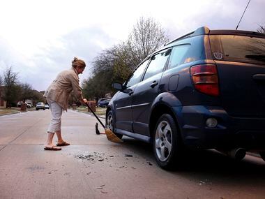 Monica Perez of McKinney sweeps up broken pieces of plastic from the wind guard that was...