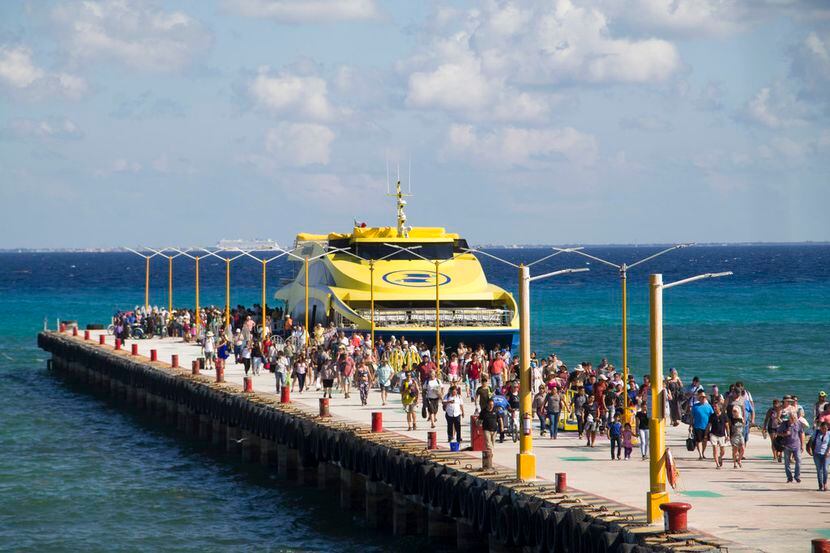 Turistas y pasajeros desembarcan de un ferry a un embarcadero en Playa del Carmen, México,...