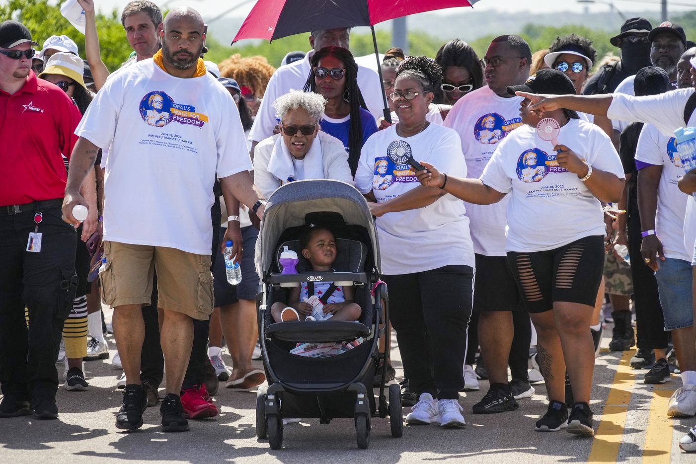 Opal Lee pushes one of her great granddaughters in a stroller as she leads walkers up...