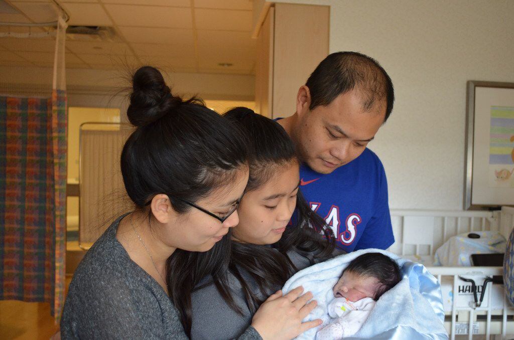 Baby James Reed Ly is held by his mother Keri Lai (left), sister Hailey Ly (center) and...