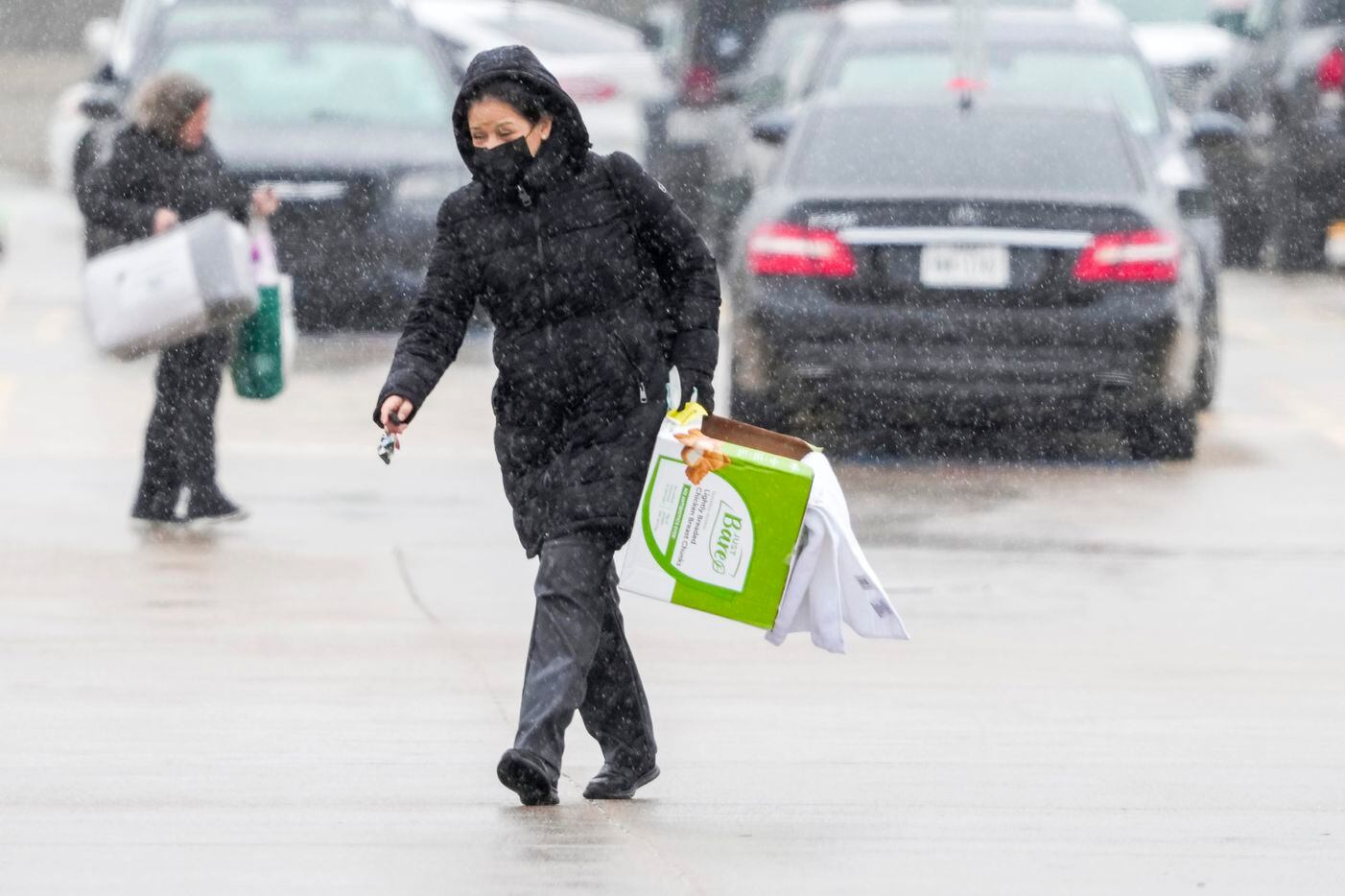 Plano „Costco“ parduotuvės pirkėjai keliauja šaltu lietumi, kai keliauja į savo automobilius...