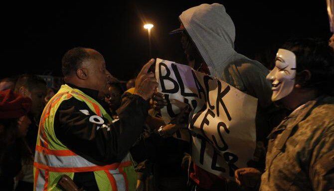 Un policía de Dallas habla con uno de los manifestantes durante una protesta en solidaridad...