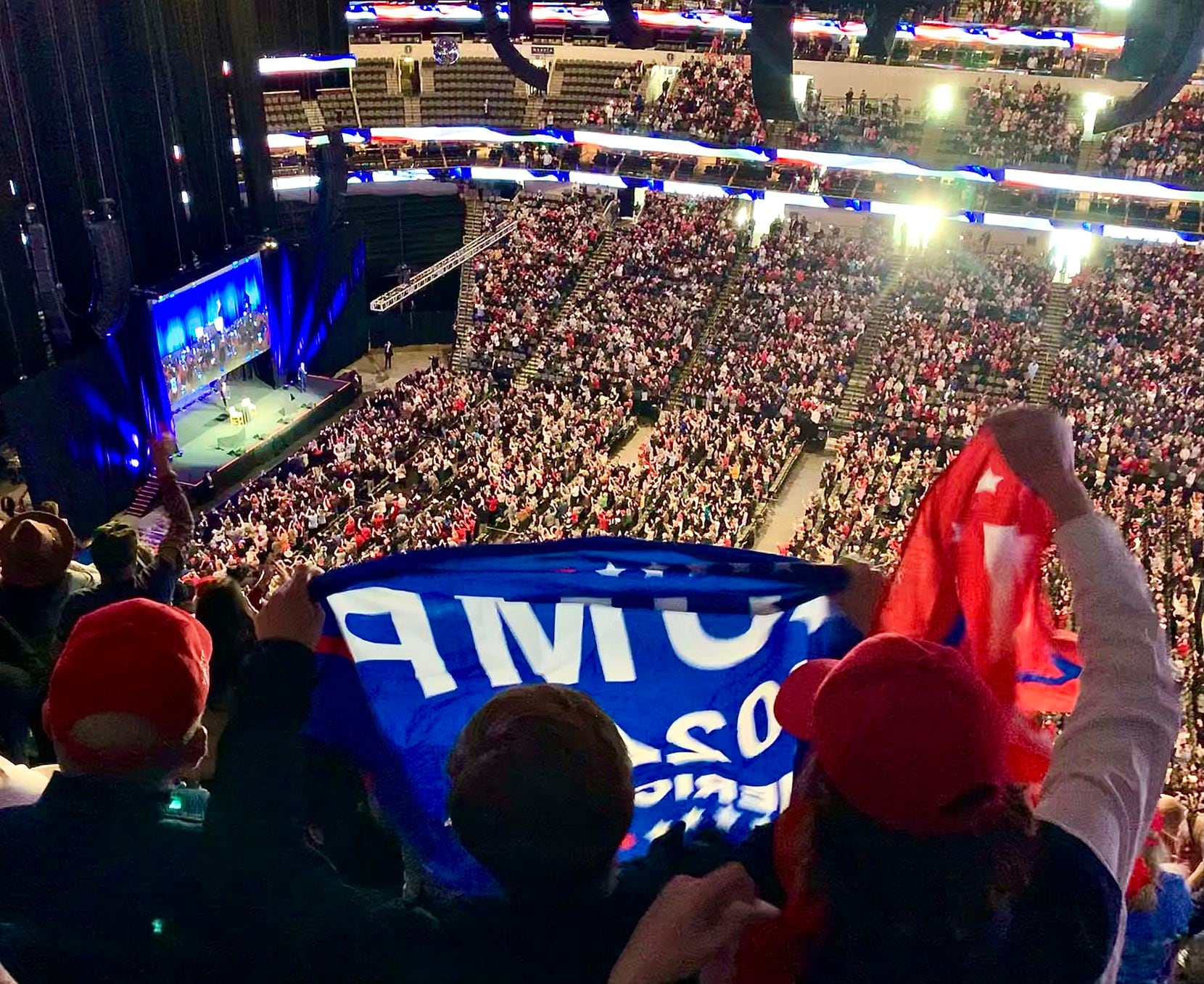 Trump supporters cheer and wave flags as former President Donald Trump walks on stage during...