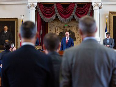 House Speaker Dennis Bonnen listens to the representatives at the back microphone as they...