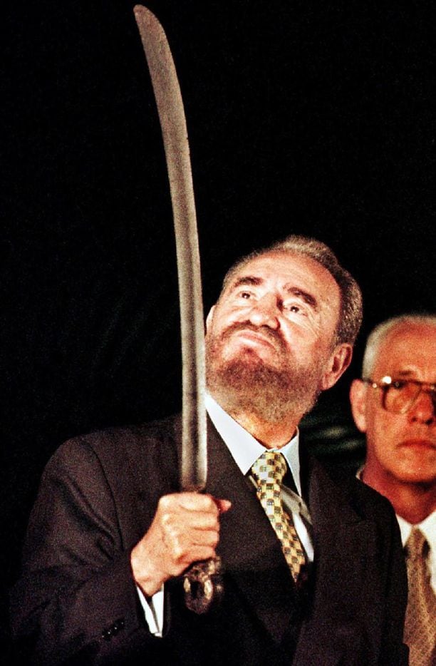 In this Aug. 24, 1998, file photo, Cuban President Fidel Castro (L) looks at a sword given...