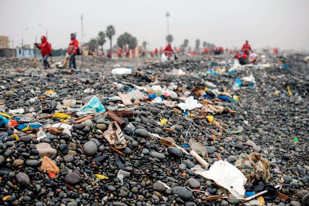 Groups of volunteers clean up plastic waste on a beach in Lima, Peru, during the World...
