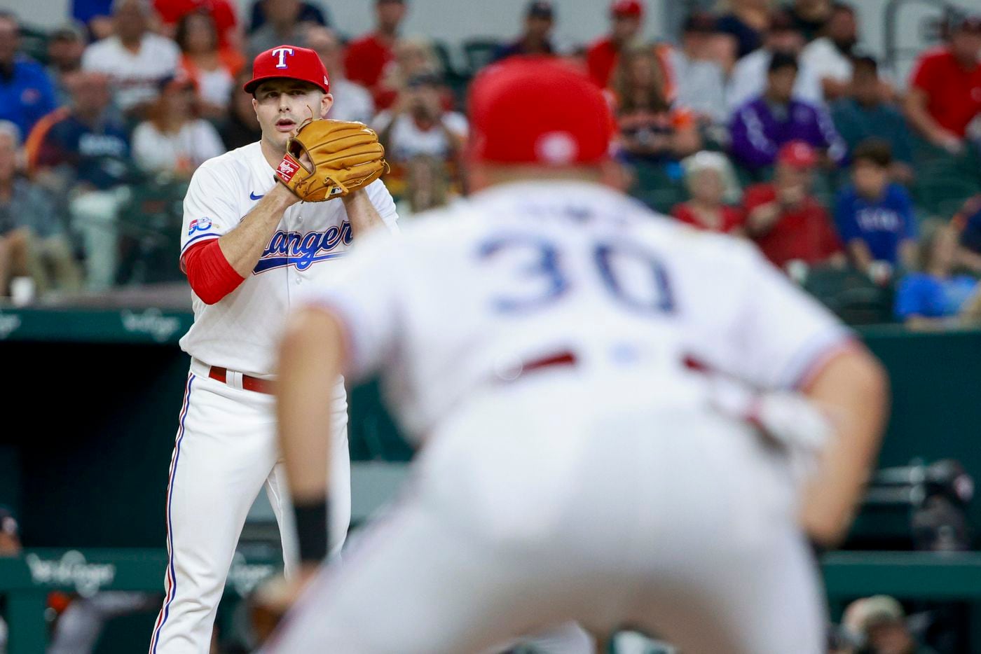 Texas Rangers relief pitcher John King (32)eyes the runner at first before delivering a...