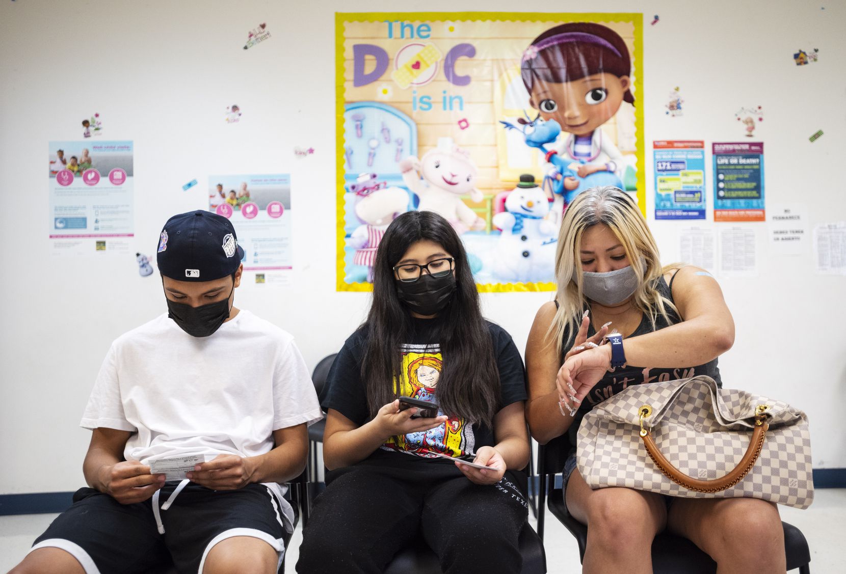Reyna Rodriguez (right) checks her watch as she waits the required 15 minutes with two of her children, Rolando (left), 17, and Madeline, 12, after the three received their second Pfizer vaccine shots at an Oak Cliff clinic on Friday, Sept. 10, 2021.