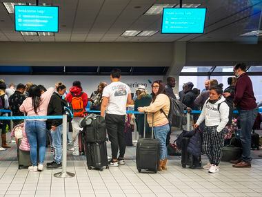 Passengers line up at an American Airlines customer service desk at Terminal C on Wednesday,...