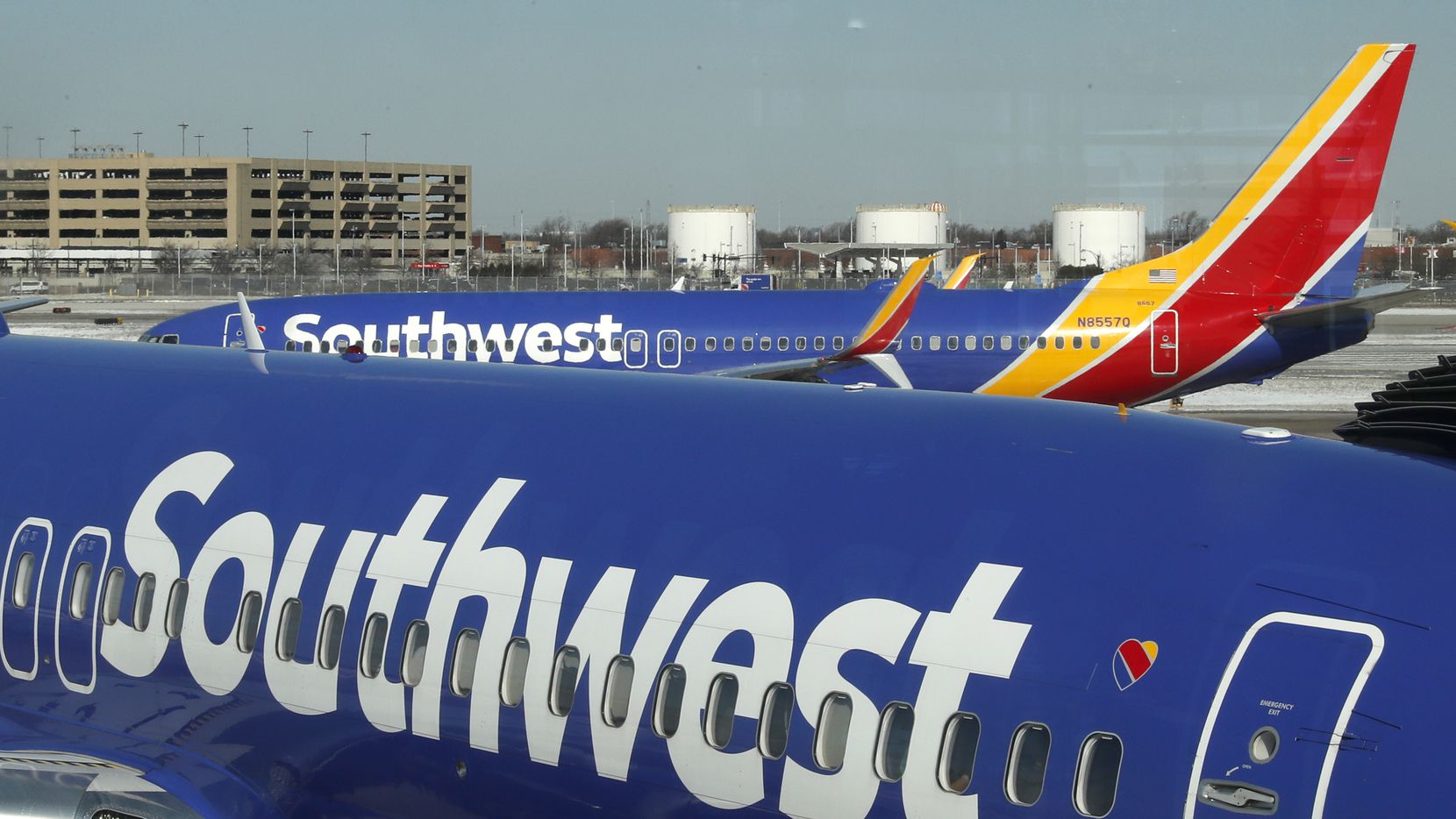 A Southwest Airlines flight, background, taxis to the runway past a loading flight at a gate...