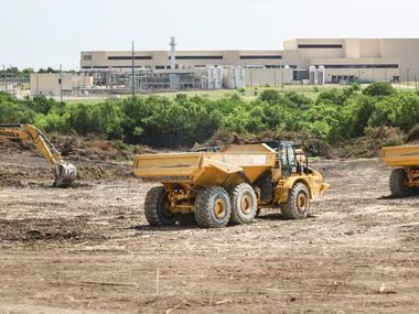 Dump trucks sit on the land where four new plants will be built by Texas Instruments in...