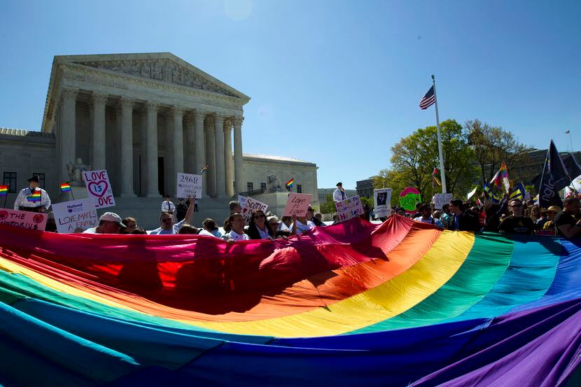 In this April 28, 2015 photo, demonstrators stand in front of a rainbow flag as the Supreme...