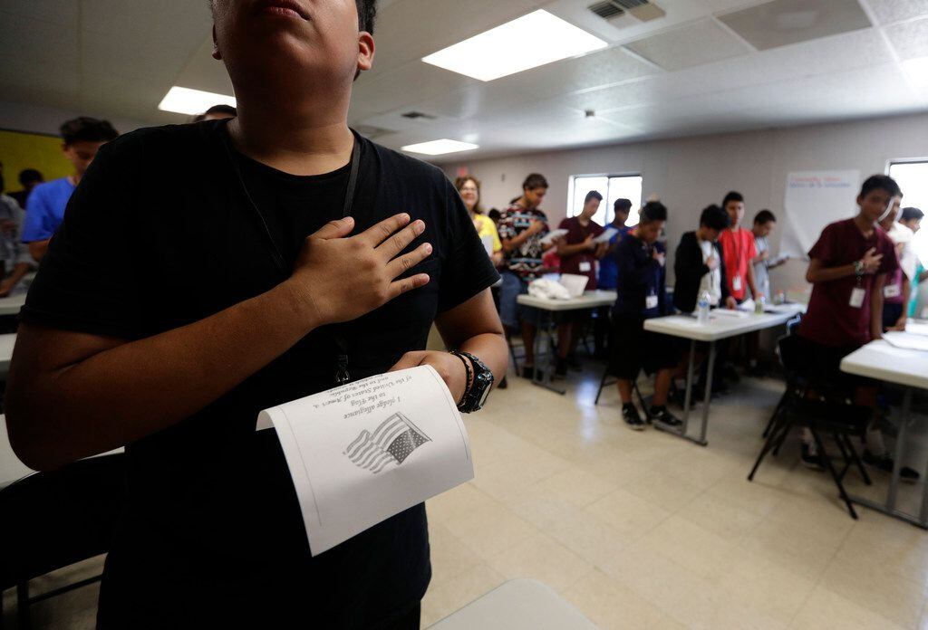 In this Tuesday, July 9, 2019, photo, immigrants say the Pledge of Allegiance in a writing...