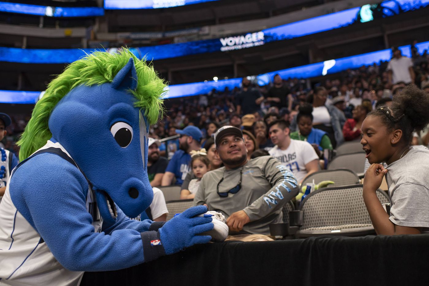 Champ, the Mavs mascot, signs a shoe for a fan during the Dallas Mavericks official watch...