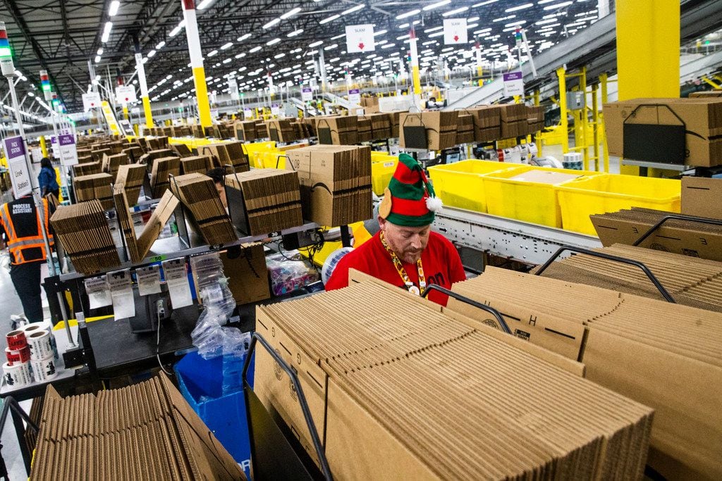 Jeffrey Tucker fills a box with air bags to cushion packages at an Amazon fulfillment center...