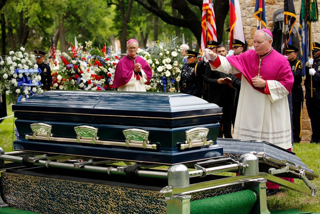 Dallas Bishop Edward J. Burns sprinkles the casket of Officer Rogelio Santander with holy...