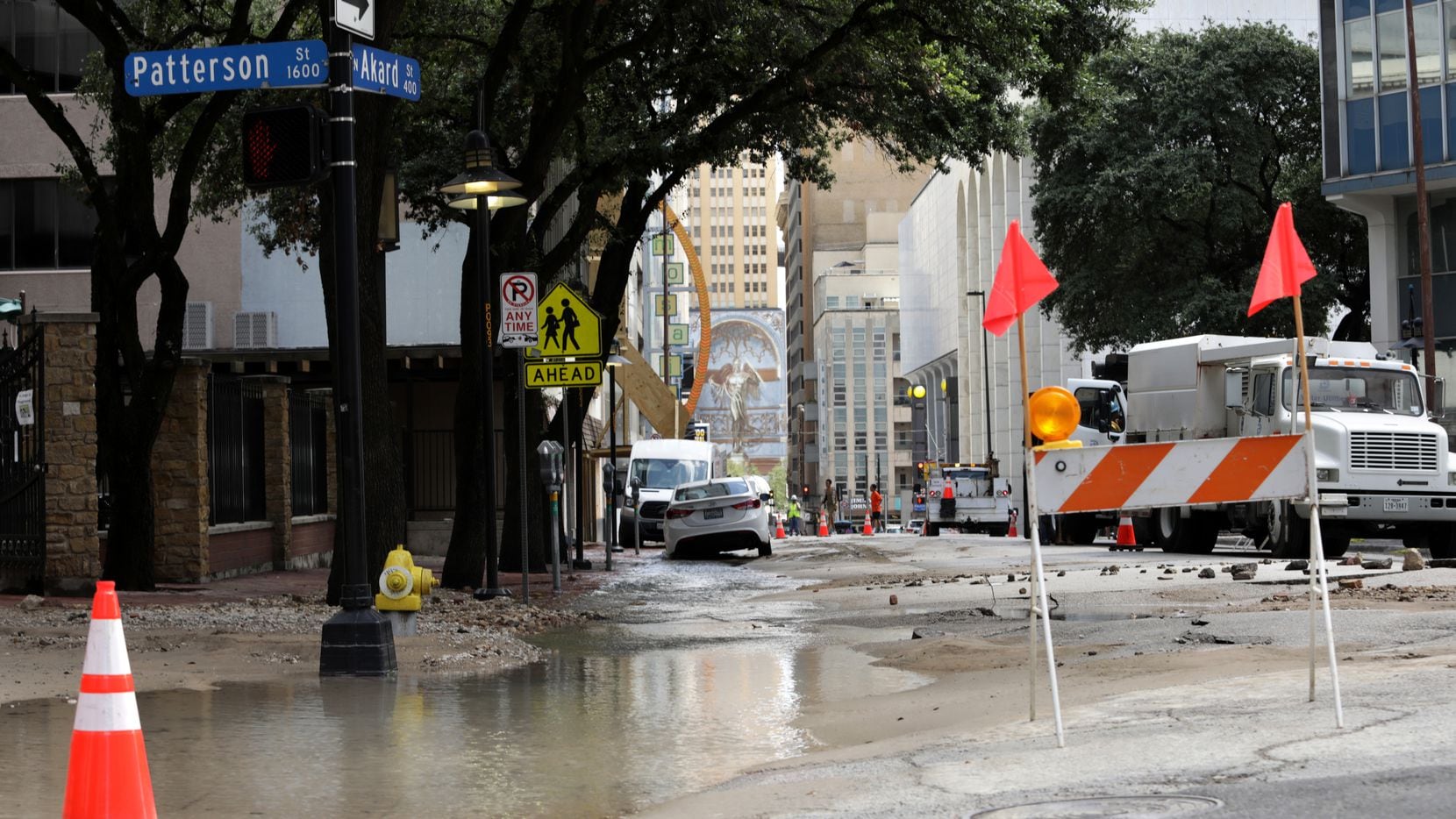 Workers secure an area damaged by a water main break at Akard Street and Patterson Street in...