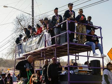 Members of the South Oak Cliff team stand on a two story trailer during a parade celebrating...