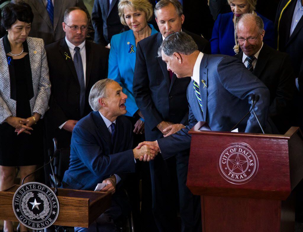 Texas Governor Greg Abbott (front, left) and Dallas Mayor Mike Rawlings (front, right) shake...