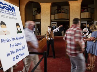 Signage at left informs patrons of the mask requirements inside the Music Hall at Fair Park as Joan Weltman, center, directs patrons for additional lines to enter a dress rehearsal of Wicked, hosted by Dallas Summer Musicals, on Sunday, Aug. 01, 2021 in Dallas.