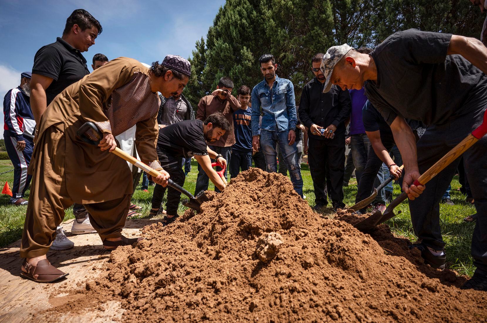 People spread dirt over Aftab Hussein's grave at Fairview Memorial Park in Albuquerque,...